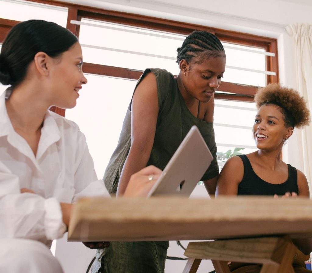 four women sitting at a table talking and writing